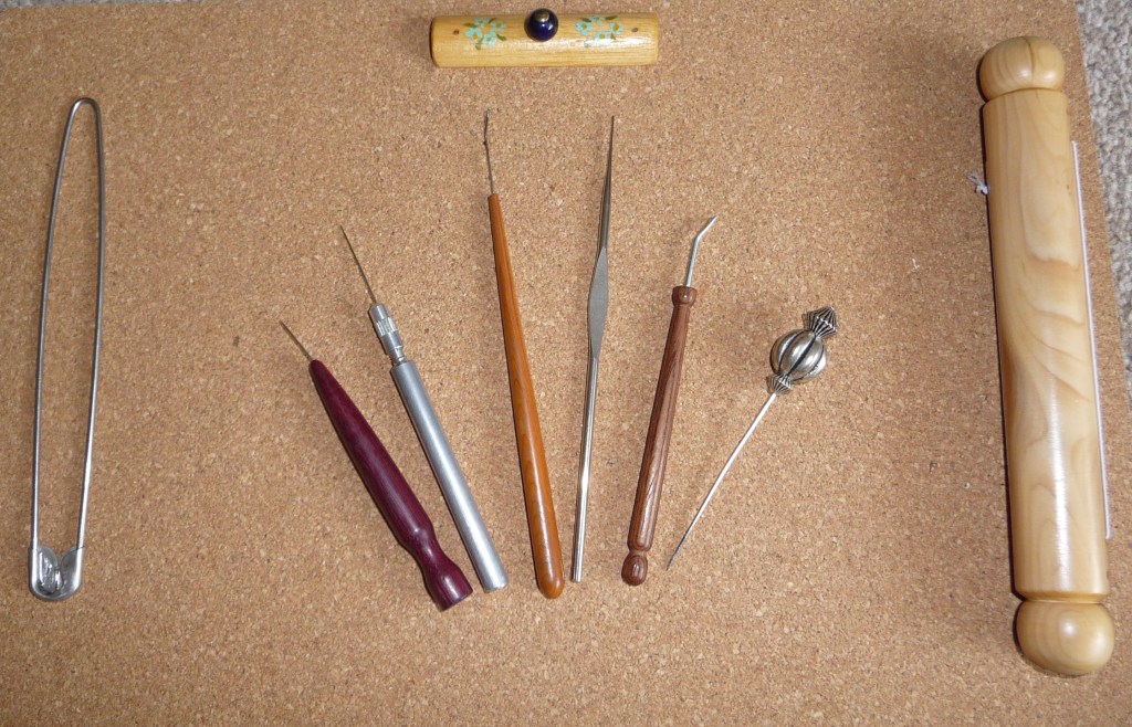 A selection of lacemaking tools laid out on a cork board