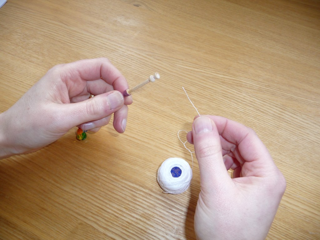 Hands holding white thread from a spool