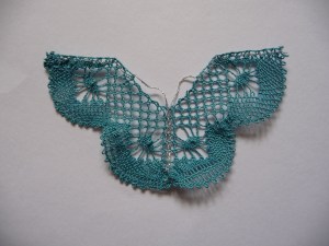 Torchon lace butterfly with ground, spiders and whole stitch edge. Worked in teal and silver thread.  